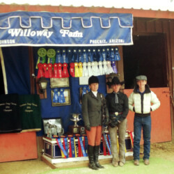Joan McKenna Jr., Kathy McCarthy, and Terry McKenna stand in front of the ribbons and trophies won by Foxglove and Kerrymor farms at the West Coast Connemara Show in August 1986 in Ventura, California. Willoway Farm was the farm name of Dave and Kathy Johnson, who served as trainers for the show.